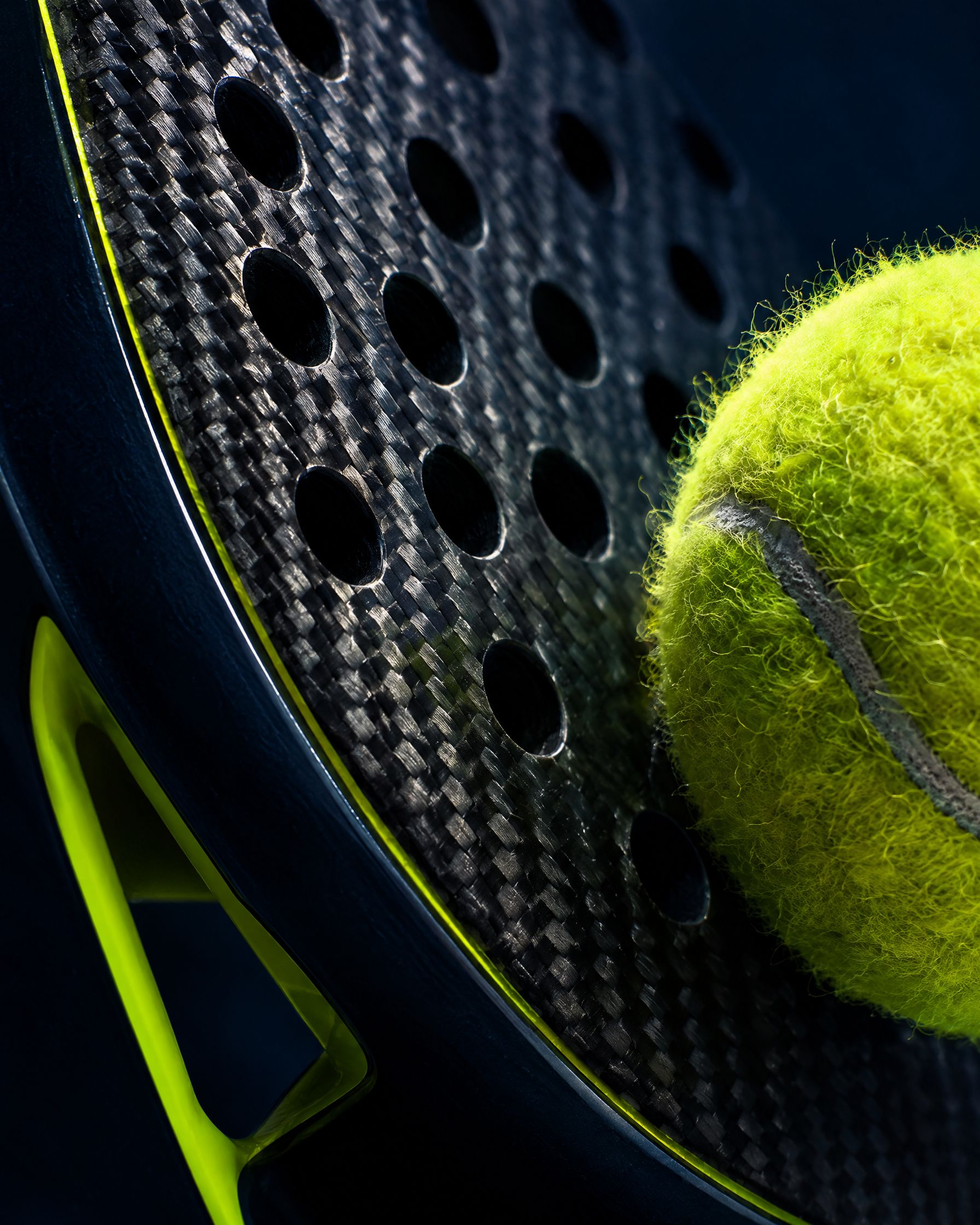 Close-up of a carbon racket face and a padel ball