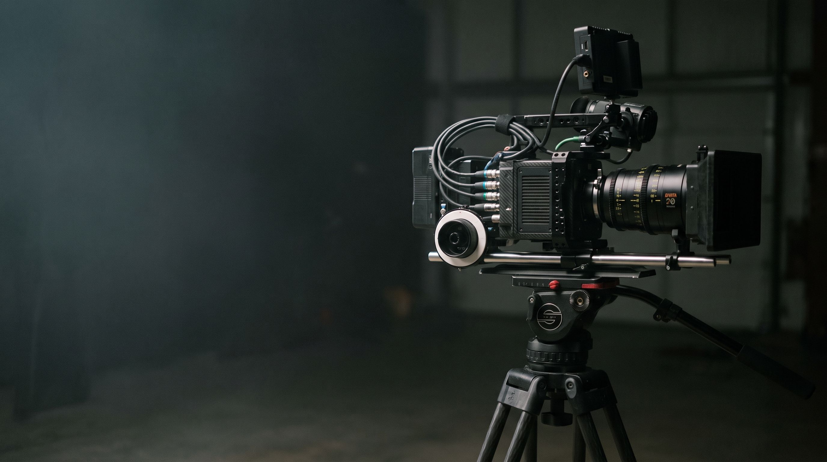 A cinema camera on a tripod in a dark studio
